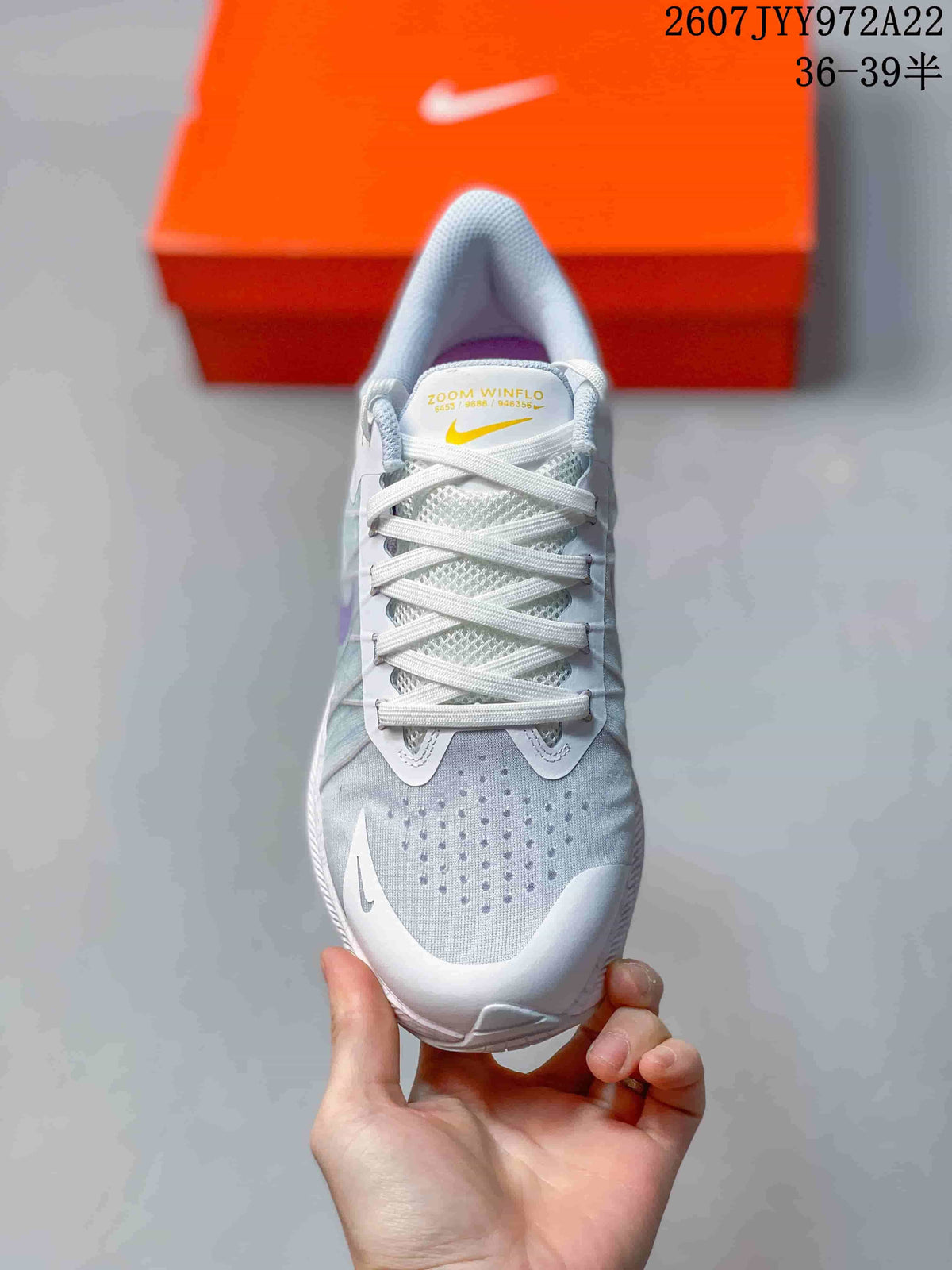 Top view of a light gray Nike running shoe showing the lace-up closure, perforated toe area, and yellow tongue branding.