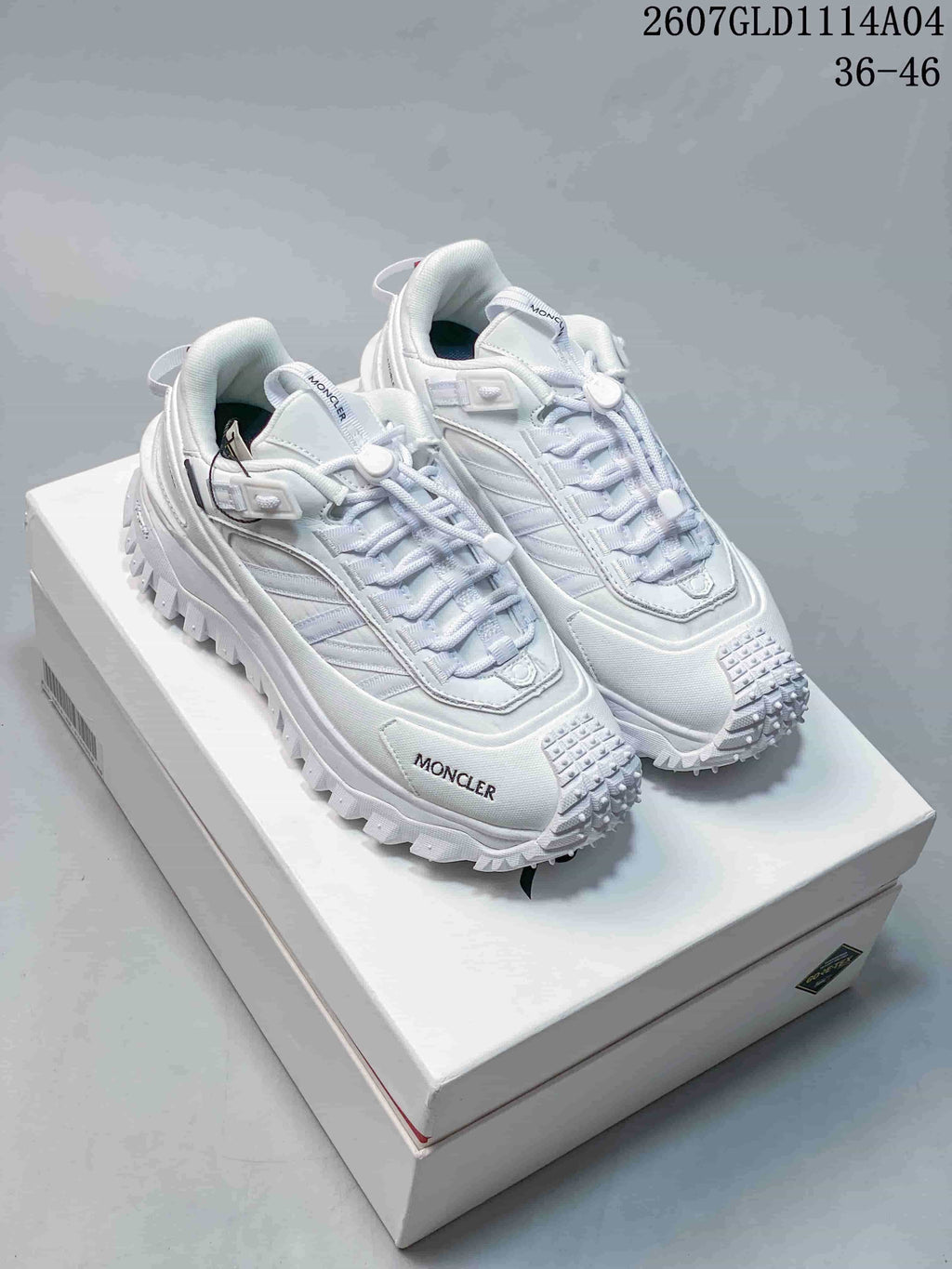 Pair of white Moncler Pacey low-top sneakers displayed on a white shoe box, with size range 36-46 and style code 2607GLD1114A04 visible at the top.