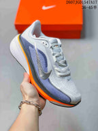 Angled side view of a Nike Pegasus 42 shoe showing the white and blue upper, metallic-colored swoosh and orange midsole.