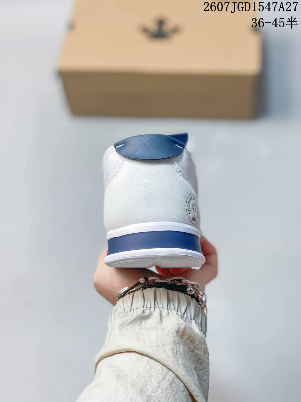 Rear view of the white sneaker with a blue heel accent and circular side marking.
