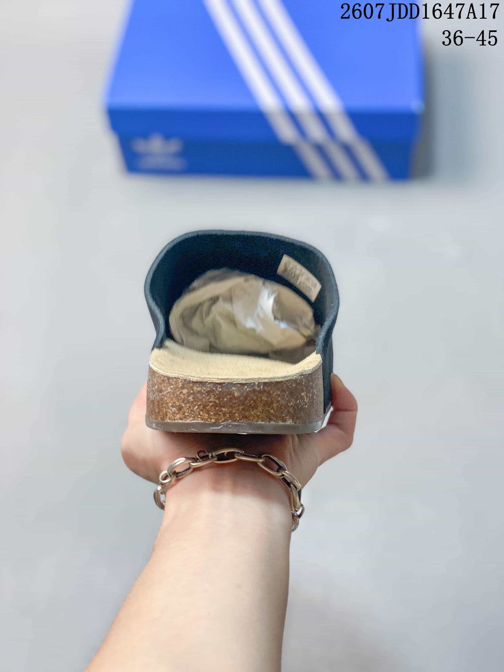 Rear view of a black adidas slide showing the covered upper, beige footbed, and brown-toned sidewall.
