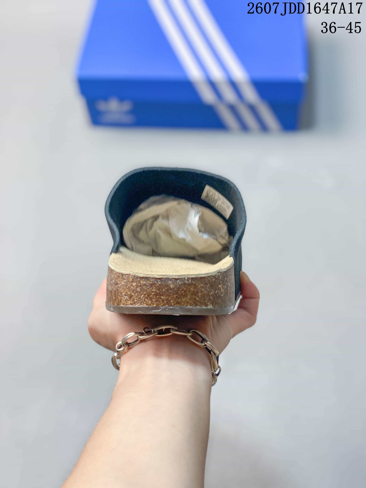 Rear view of a black adidas slide showing the covered upper, beige footbed, and brown-toned sidewall.