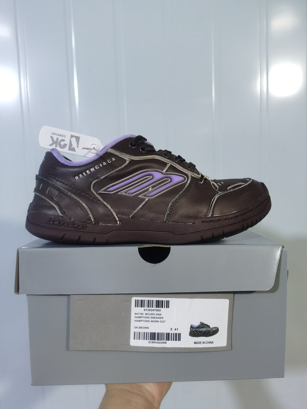 Side profile of the dark brown Balenciaga sneaker displayed on its box; the box label shows Hampton Sneaker, DK.BROWN, and E 41.