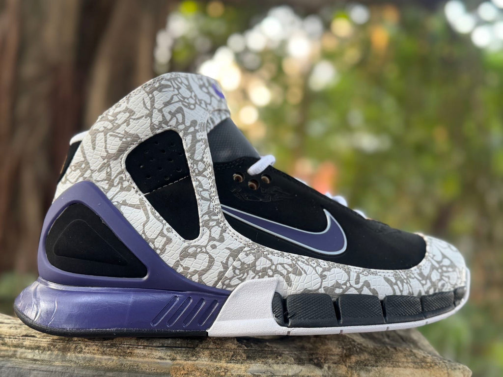 Side view of black high-top Nike sneakers with grey patterned overlays and purple-blue accents