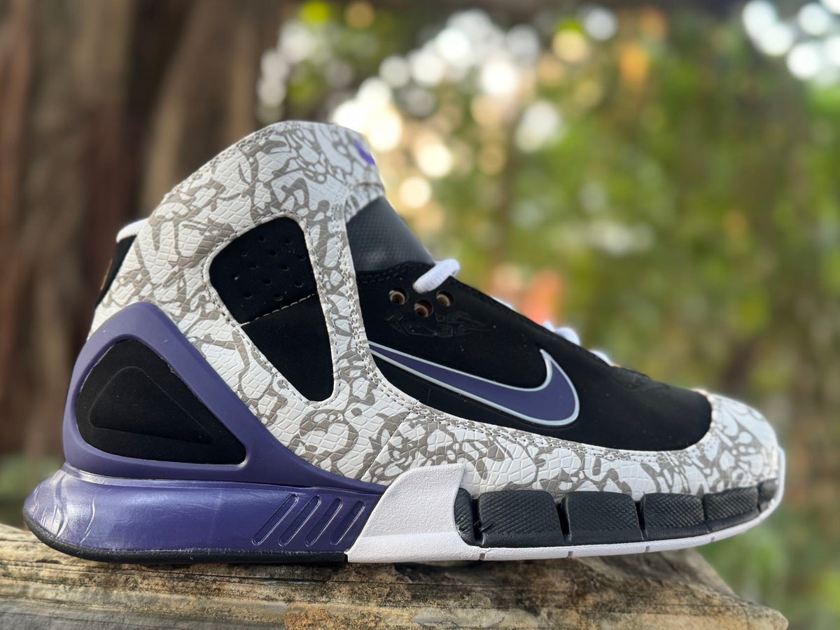 Side view of black high-top Nike sneakers with grey patterned overlays and purple-blue accents