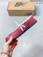 Side view of the red low-profile sneaker showing layered panels, white laces, and the dark outsole.