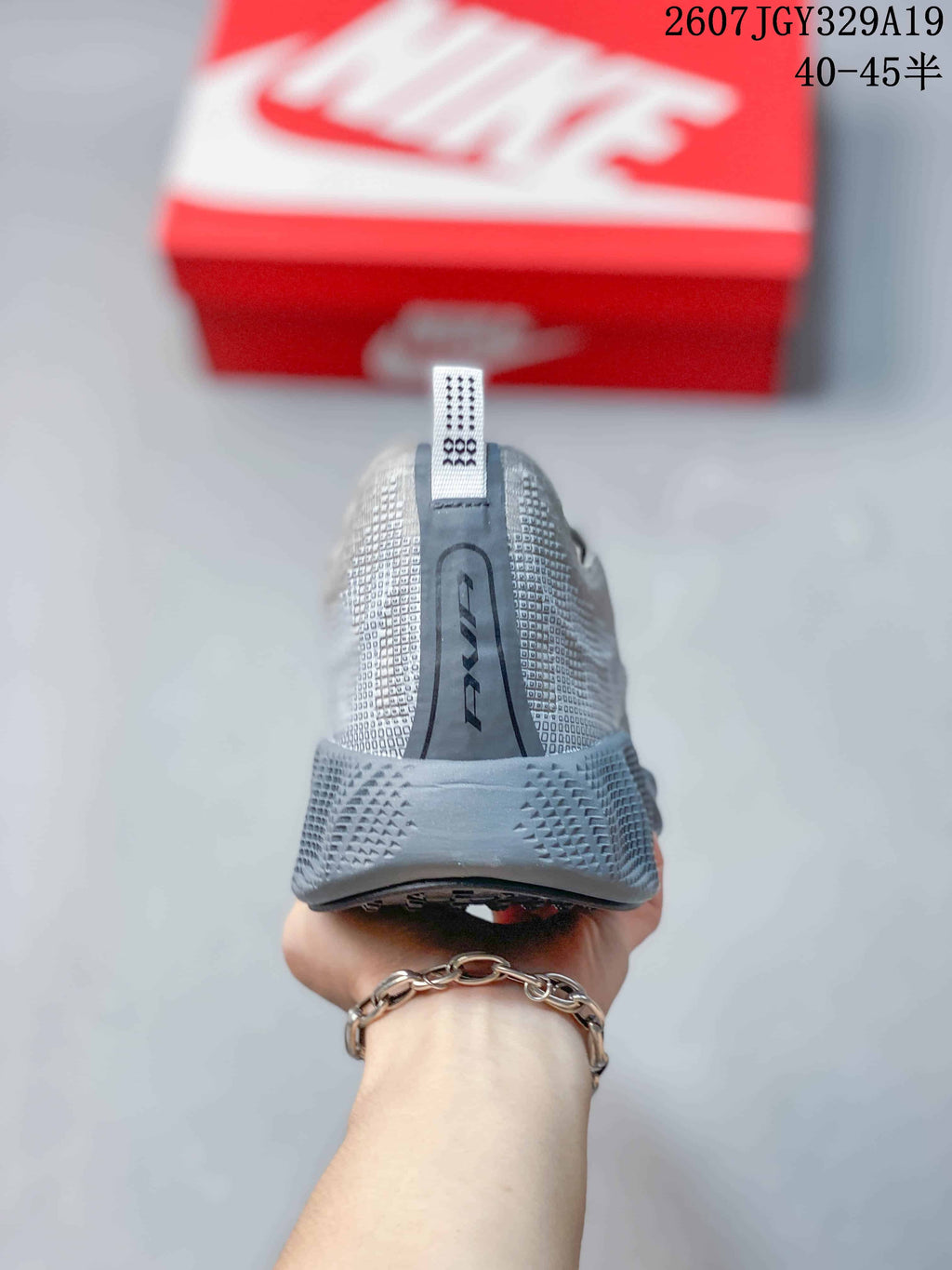 Rear view of the gray sneaker showing the heel pull tab, textured upper, and raised heel section.