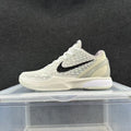 Side view of an ivory-toned Nike basketball sneaker with raised star details, a black Swoosh, and a pale Zoom-branded midsole.