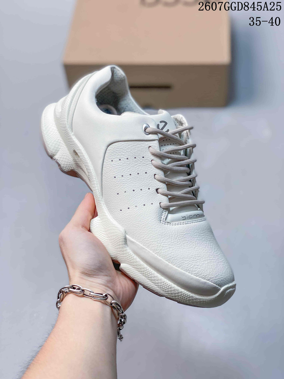 Close side view of a white ECCO Biom C sneaker held in hand, showing the perforated upper panel, padded collar and white outsole.