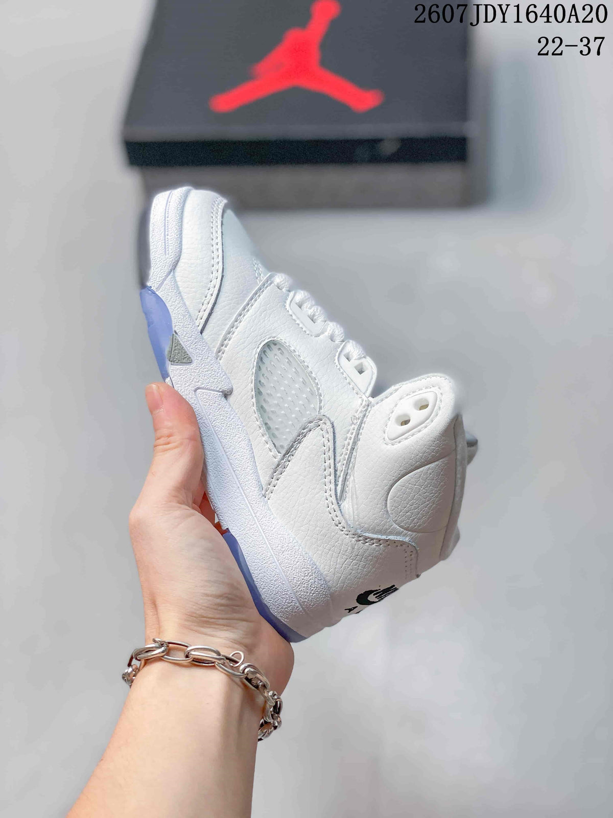 Side view of the white mid-top sneaker showing layered panels, perforated detailing, and the translucent outsole.