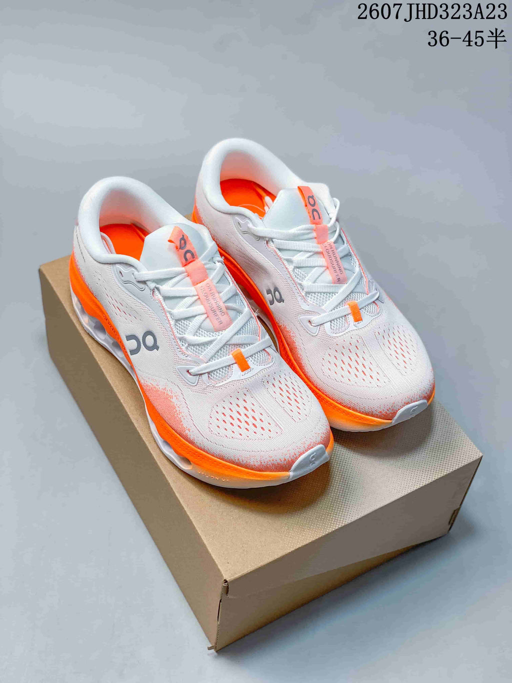 Pair of white and orange On Cloudtilt Remix sneakers displayed on a shoebox.