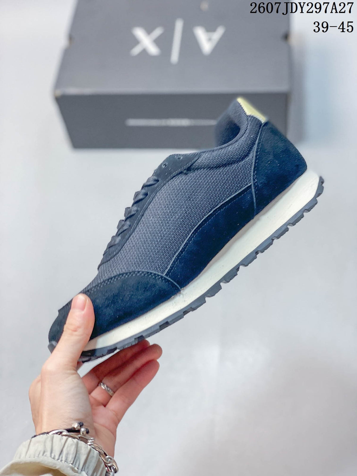 Side profile showing the navy upper, layered panels, light-colored midsole, and textured outsole.