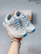 Pair of white and light gray On running shoes with blue accents, shown from an angled top view.