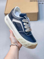 Angled side view showing the navy low-top sneaker, white side panel, laces, and textured off-white sole.
