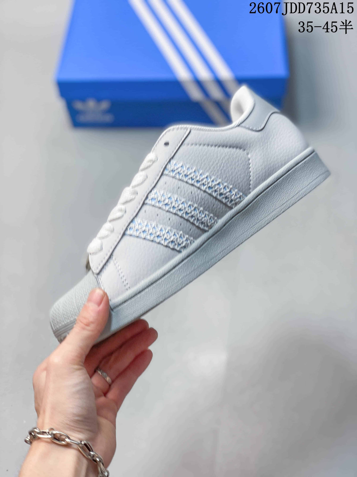 Side view showing the white and gray upper, textured three stripes, and low-profile sole.