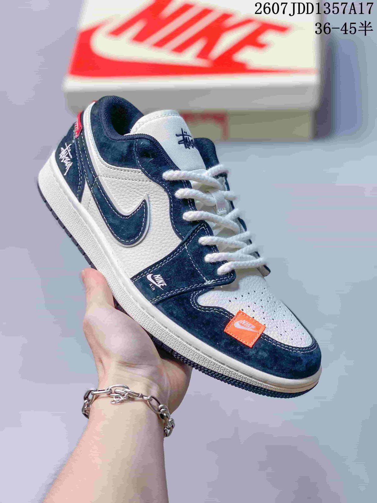 Navy and white low-top sneaker with white laces, orange tongue patch and contrasting dark outsole.