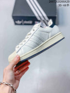 Side profile showing the white upper, Adidas stripe details, light midsole, and dark outsole edge.