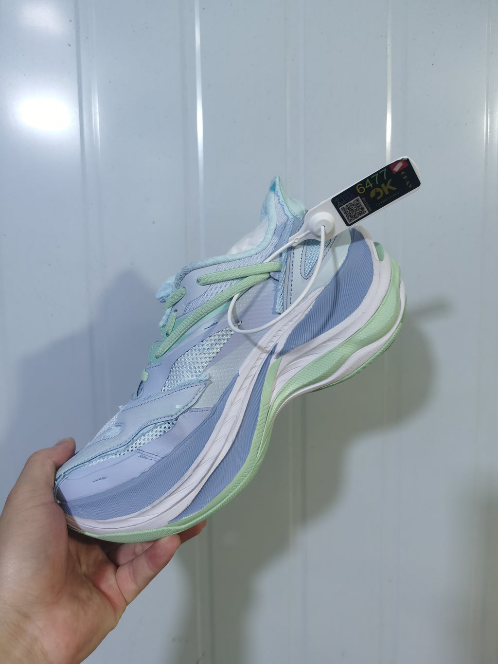 Angled view of the pale blue and green sneakers highlighting the laces, mesh panels, and raised sole.