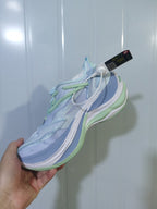 Angled view of the pale blue and green sneakers highlighting the laces, mesh panels, and raised sole.
