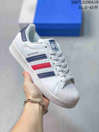 White adidas Superstar sneaker with navy and red serrated stripes.