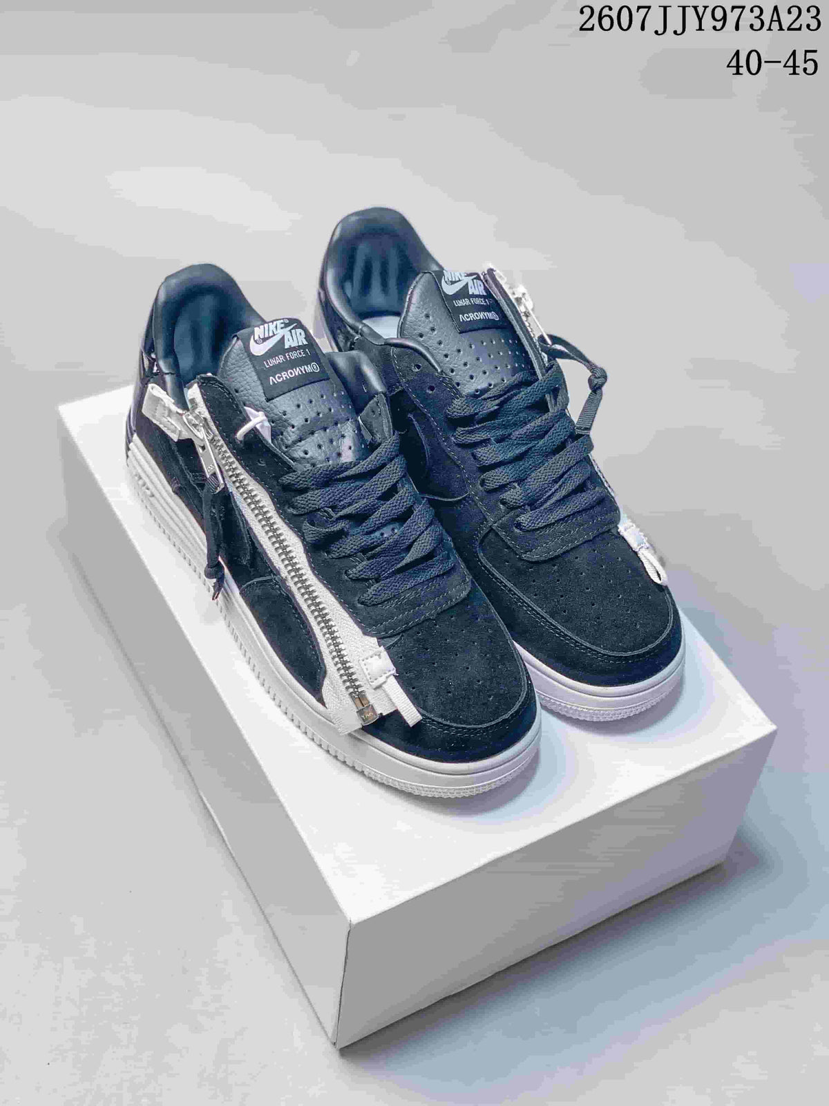 Pair of black Nike Lunar Force 1 x ACRONYM low-top sneakers on a box, showing side zippers, laces, perforated toe panels, and a white outsole; image text shows product code 2607JJY973A23 and size range 40–45.