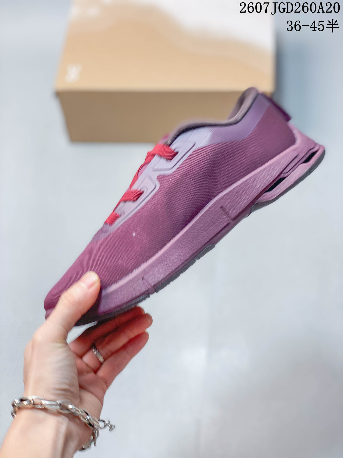 Side view of the plum-purple sneaker showing the layered sole, textile-looking upper, and sculpted heel area.
