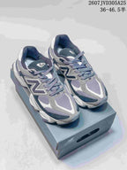 Pair of grey and navy New Balance 9060 sneakers displayed on a shoebox.
