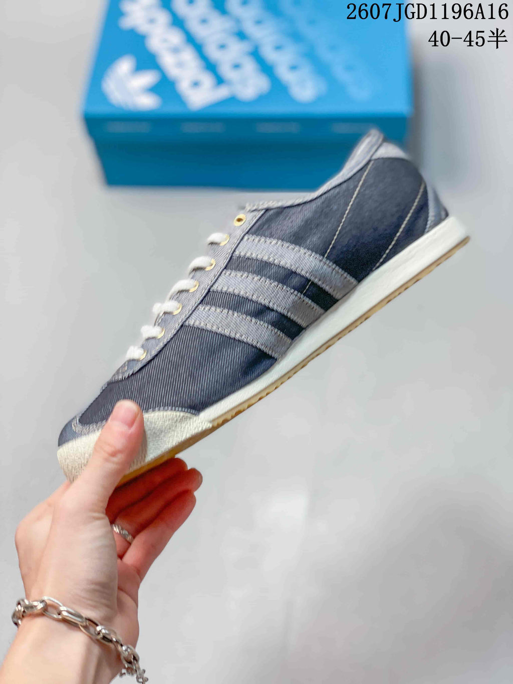 Side profile showing the dark upper, contrasting three-stripe details, light midsole, and gum outsole.