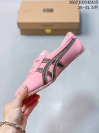 Side view of the pink sneaker showing brown and metallic stripe detailing and the low-profile sole.