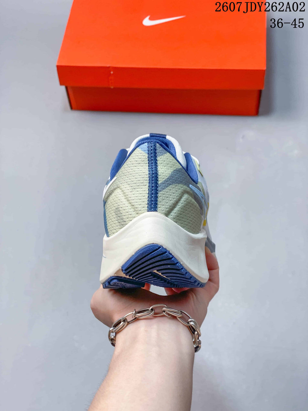 Rear view of a Nike Pegasus 38 shoe with a pale green heel panel and blue trim.