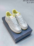 Pair of white and yellow Nike Air Force 1 ’07 LV8 low-top sneakers displayed on a shoebox, showing the decorated toe boxes and yellow collar lining.