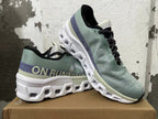 Pair of sage-green On Running shoes shown at an angle, highlighting the upper and sculpted sole.