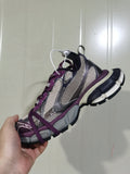 Close-up side view of purple and grey Nike 1269 sneakers with mesh-style panels, dark overlays, purple laces, and a segmented outsole.
