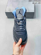 Front view of the sneaker showing its silver-toned tongue, dark laces and light blue collar