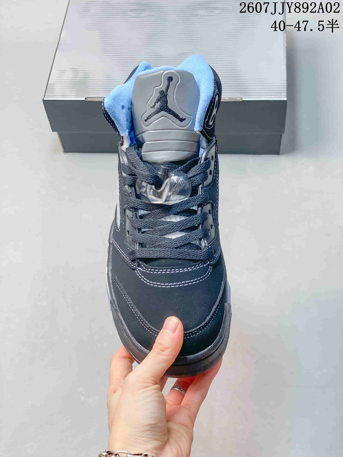 Front view of the sneaker showing its silver-toned tongue, dark laces and light blue collar