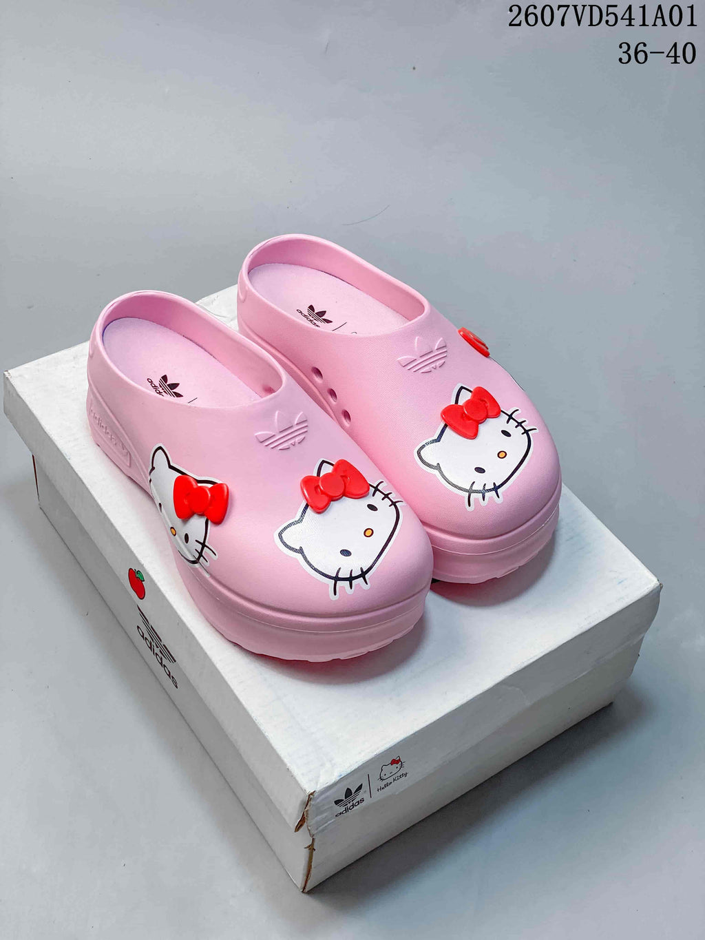 Pair of pink Hello Kitty platform mule clogs with red bow details.