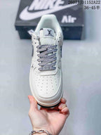 Top view of the white sneaker showing the perforated toe box, patterned laces, tongue, and metal-toned lace detail.