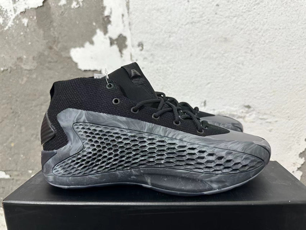 Side view of a black Adidas high-top basketball shoe with a textured grey side panel and marbled outsole.
