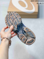 Close-up of the patterned outsole of an ASICS sneaker, showing gray, blue, and metallic bronze tread sections.