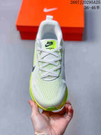 Top view of the white lace-up sneaker with neon green accents and Vomero 18 tongue branding.
