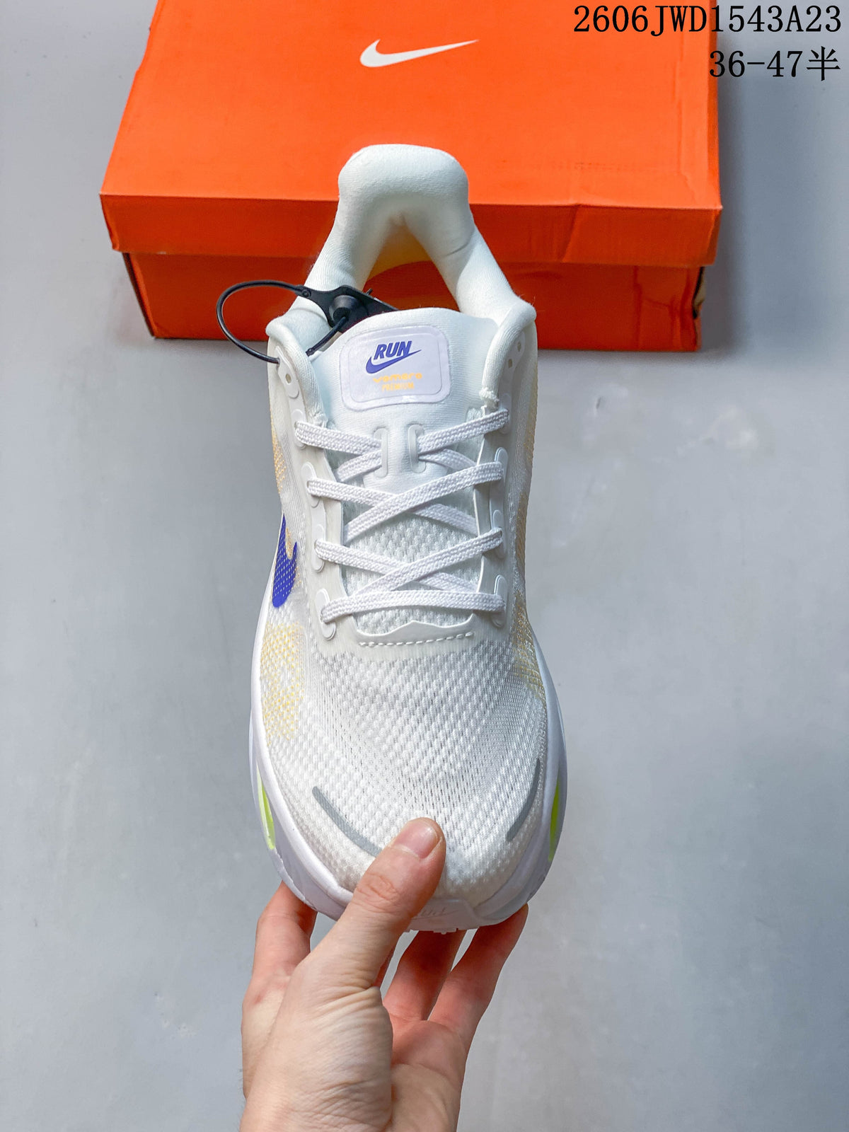 Front view of the white lace-up running shoe with purple tongue branding and gray toe accents.