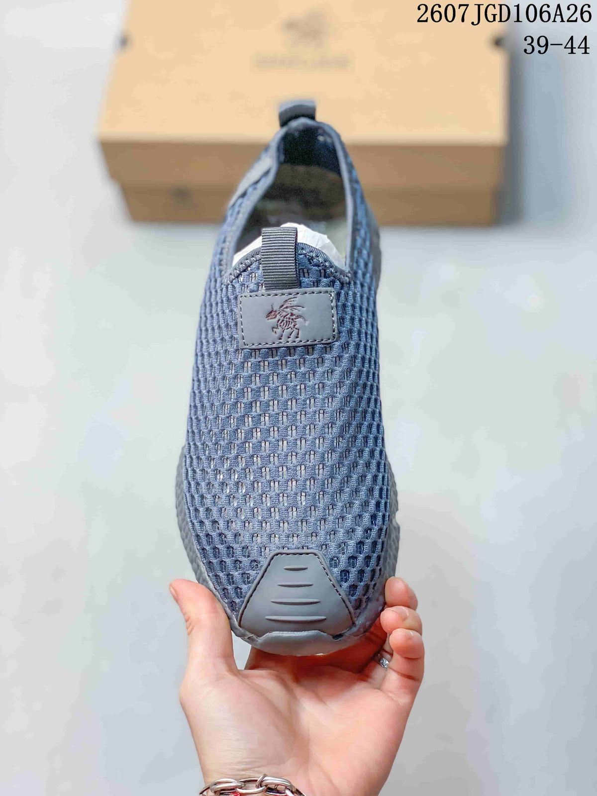 Top view of the sneaker showing the blue-gray mesh upper, front pull tab, branding patch, and protective toe panel.