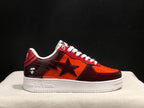 Side profile highlighting the burgundy heel and toe overlays, orange mid-panel and white Bape-branded sole.