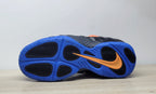 Underside of black Nike Air Foamposite Pro sneakers showing a bright blue outsole and orange Swoosh.