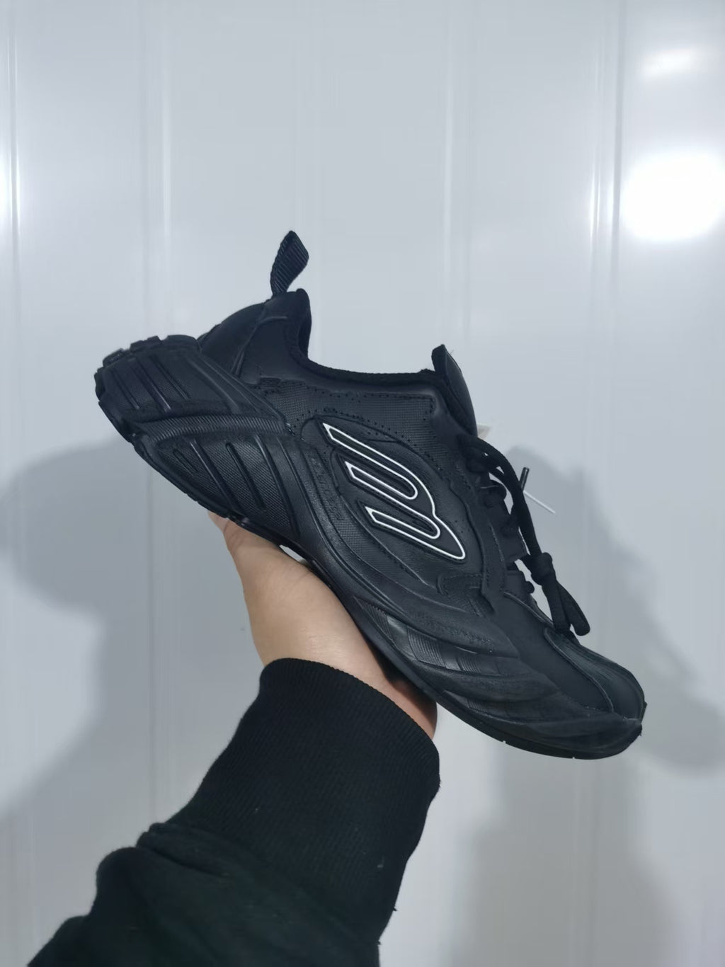 Side view of a black chunky lace-up sneaker held against a light background.