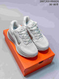 Pair of white and grey Nike Vomero 18 SE sneakers displayed on an orange shoebox.