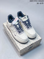 Pair of white Nike Air Force 1 '07 low-top sneakers with navy laces and gray details displayed on a patterned shoebox.