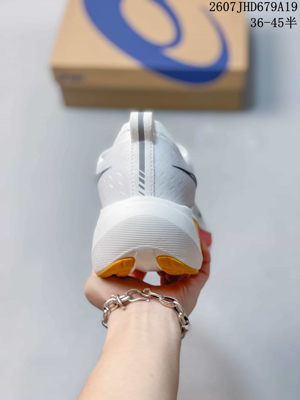 Rear view of the white running shoe showing the heel pull tab, raised sole, and yellow outsole accents.