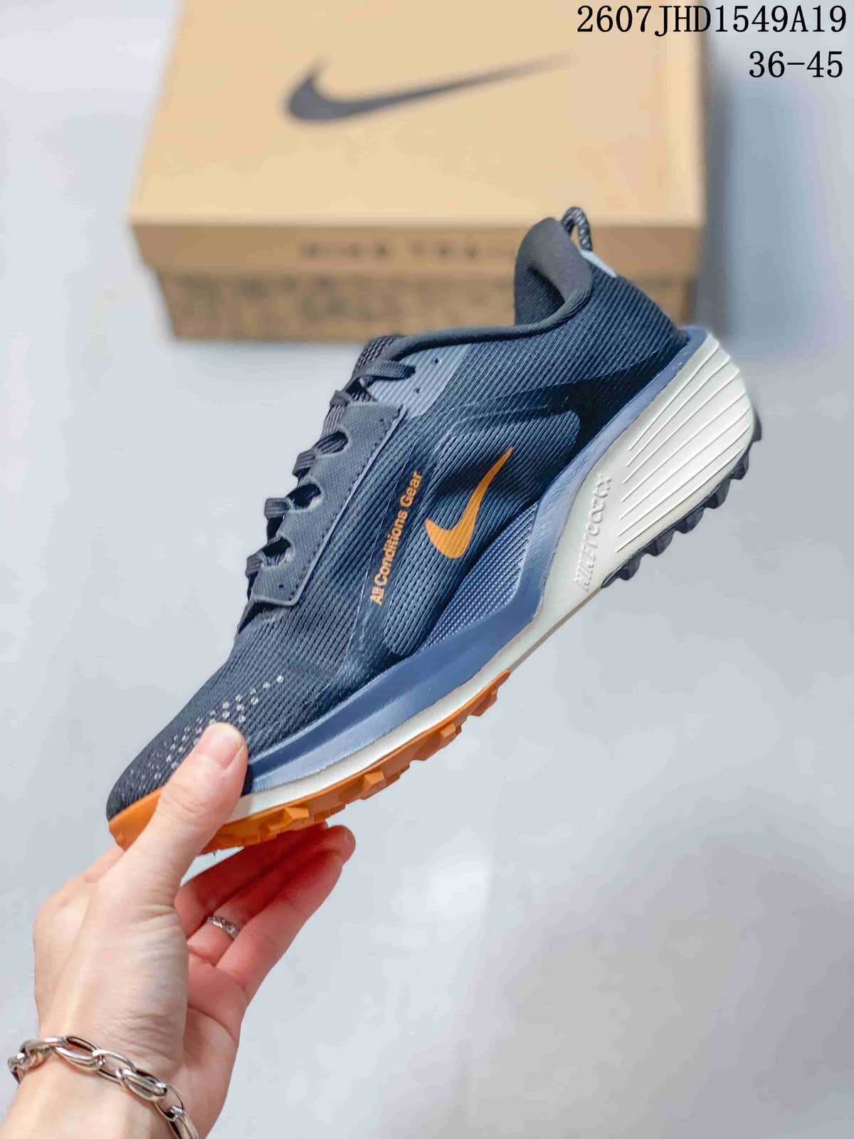 Side profile showing the mesh-textured upper, orange Swoosh detail, layered midsole, and treaded outsole.
