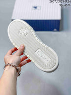 Bottom view of the white sneaker showing a repeating zigzag outsole pattern and an MLB-marked central panel.